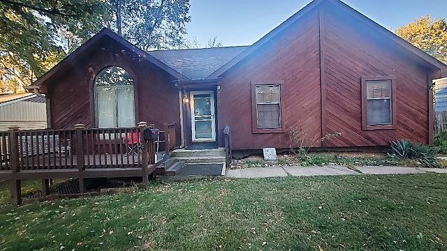 back of property featuring a lawn and a deck