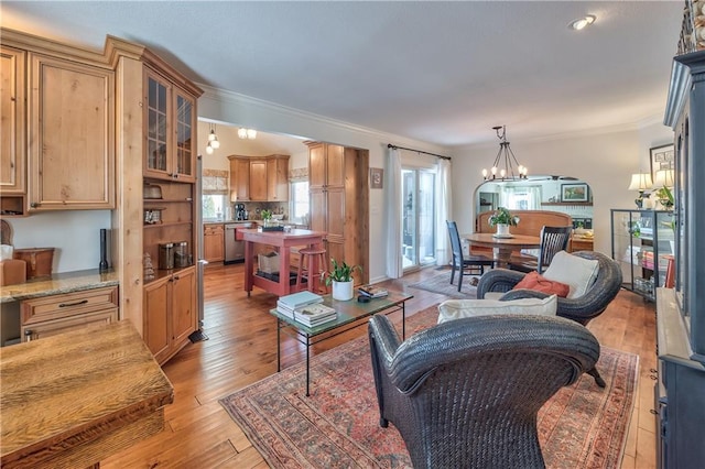 living room featuring light wood-style floors, a notable chandelier, and ornamental molding