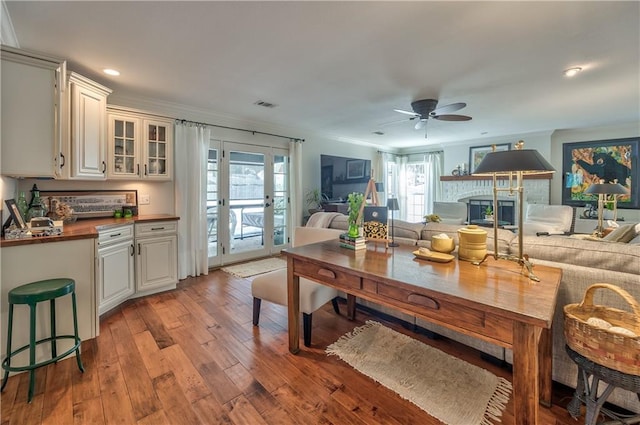 living area with ornamental molding, visible vents, a fireplace, and light wood finished floors