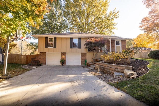 raised ranch featuring brick siding, fence, driveway, and an attached garage