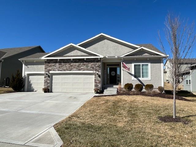 ranch-style house with concrete driveway, a front lawn, an attached garage, and stucco siding