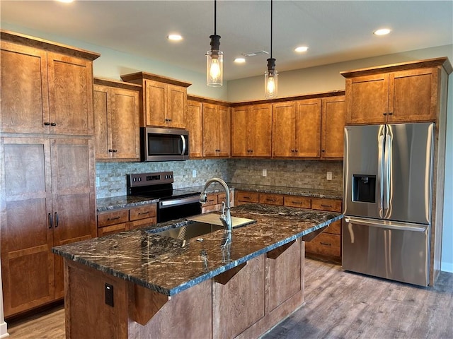 kitchen featuring stainless steel appliances, brown cabinetry, a sink, and decorative backsplash