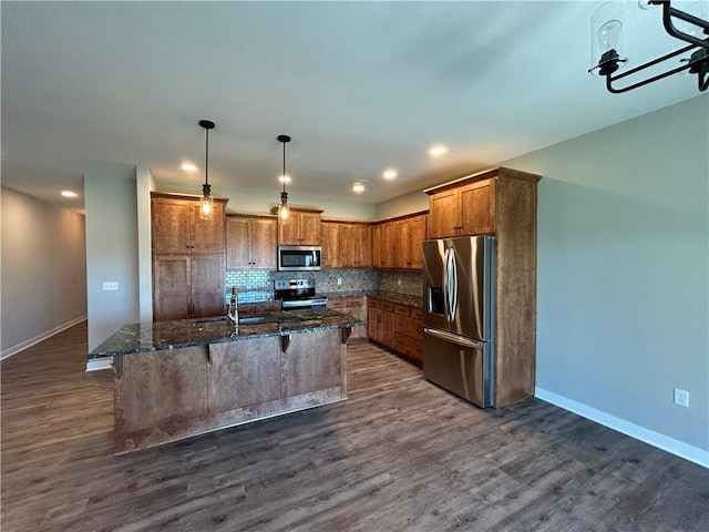 kitchen with dark wood-style floors, backsplash, a kitchen bar, stainless steel appliances, and a sink