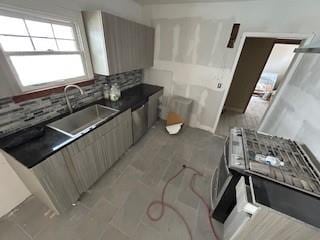 kitchen featuring a sink, stainless steel dishwasher, decorative backsplash, dark countertops, and modern cabinets