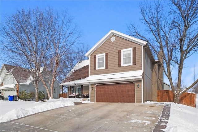 view of front facade featuring a garage, concrete driveway, and fence