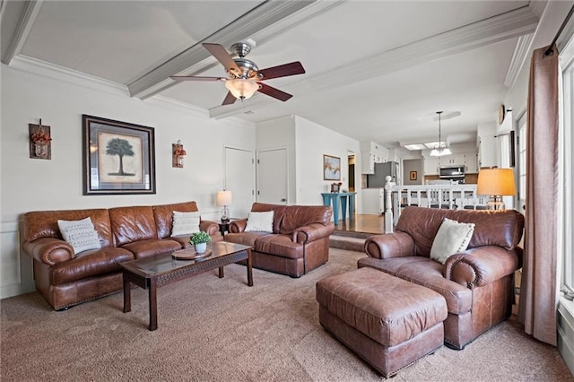 living room with ceiling fan with notable chandelier, beamed ceiling, light colored carpet, and crown molding