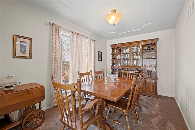 dining space featuring dark colored carpet, visible vents, and baseboards