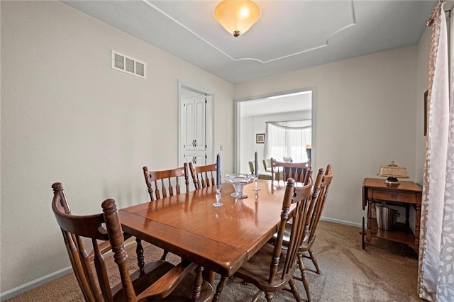 dining area with baseboards, visible vents, and light colored carpet