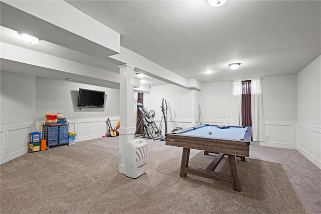 playroom featuring wainscoting, carpet flooring, a decorative wall, and a textured ceiling