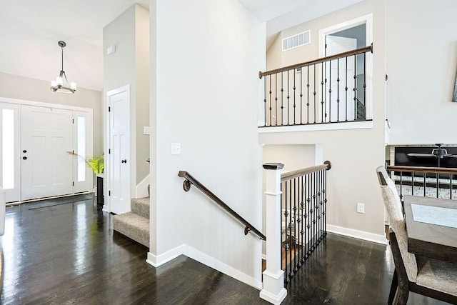 entrance foyer with visible vents, dark wood finished floors, a notable chandelier, and baseboards