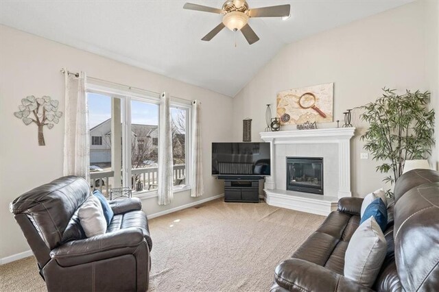 living room featuring baseboards, vaulted ceiling, a tiled fireplace, and light colored carpet