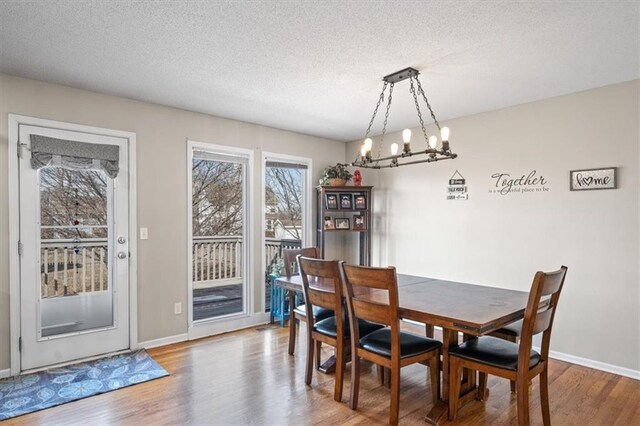 dining room with an inviting chandelier, a textured ceiling, and wood finished floors