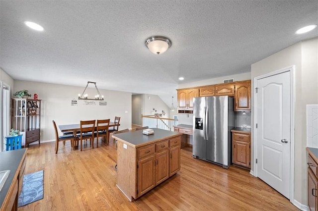 kitchen featuring brown cabinetry, a kitchen island, stainless steel refrigerator with ice dispenser, and light wood-style flooring