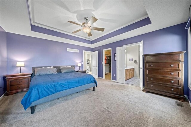 bedroom with light carpet, a spacious closet, a raised ceiling, and visible vents