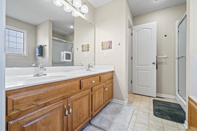 bathroom with a sink, a shower stall, baseboards, and double vanity