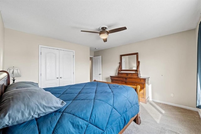 bedroom with baseboards, ceiling fan, a closet, and light colored carpet