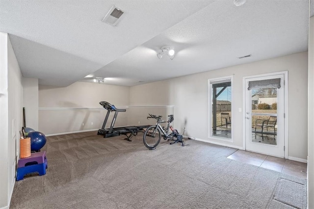 exercise room with carpet floors, visible vents, a textured ceiling, and baseboards