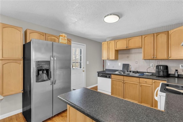 kitchen with dark countertops, white appliances, and light brown cabinets