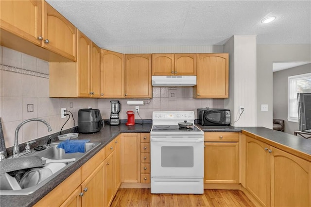 kitchen featuring dark countertops, under cabinet range hood, black microwave, and white range with electric cooktop