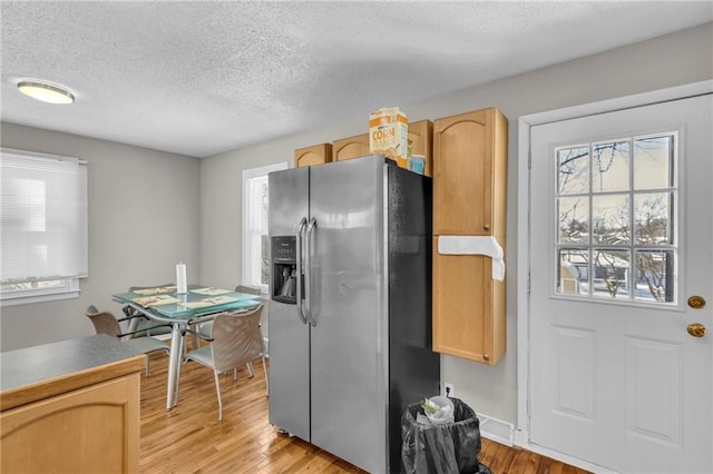 kitchen with light brown cabinetry, light wood-type flooring, and stainless steel refrigerator with ice dispenser