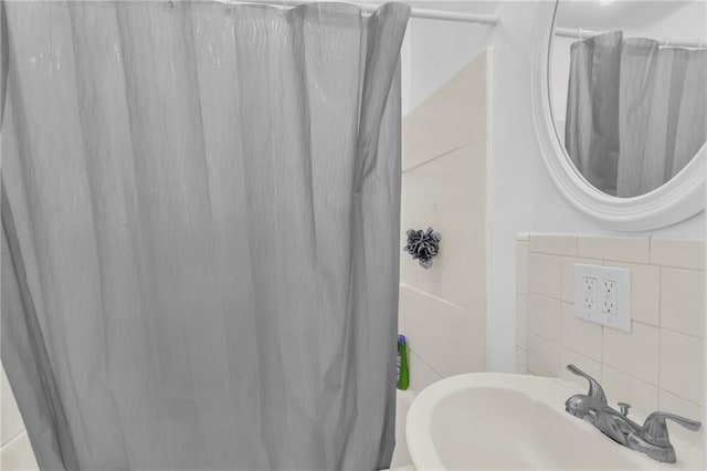 full bath featuring curtained shower, a sink, and tile walls