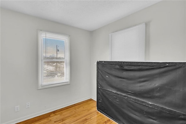 misc room with a textured ceiling, wood finished floors, and baseboards