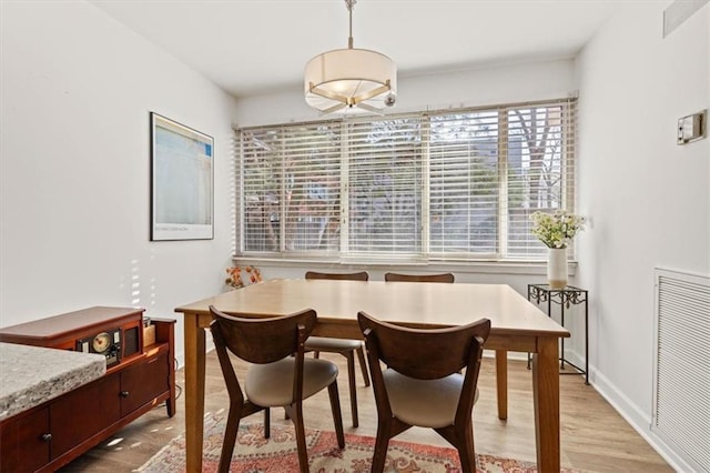 dining area with light wood-type flooring, visible vents, and baseboards