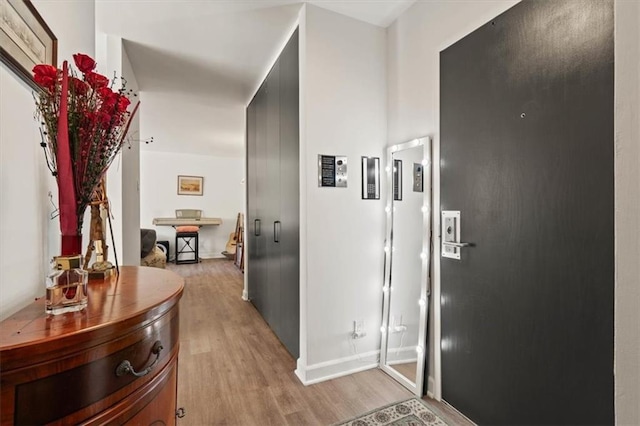 hall featuring light wood-style flooring and baseboards