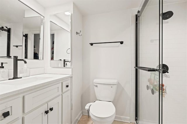 bathroom with a shower stall, toilet, vanity, and baseboards