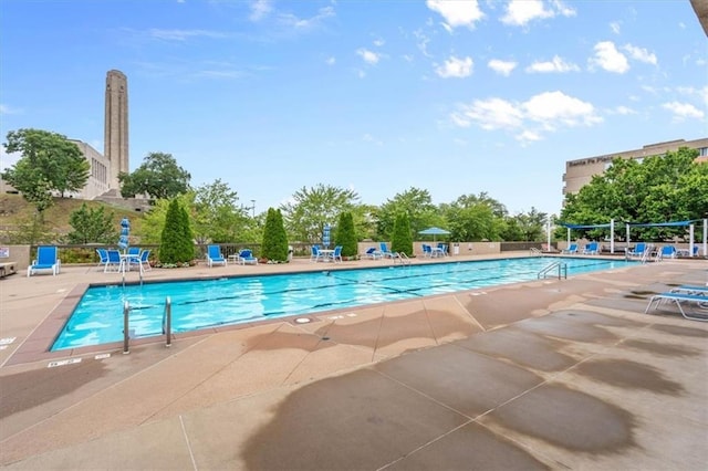 pool with a patio area and fence