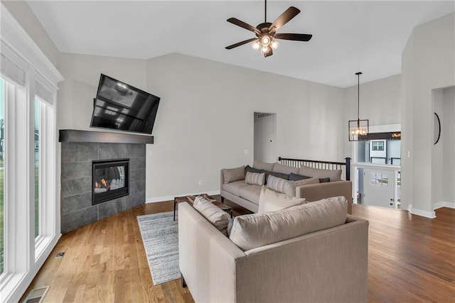 living area featuring vaulted ceiling, a fireplace, wood finished floors, and visible vents