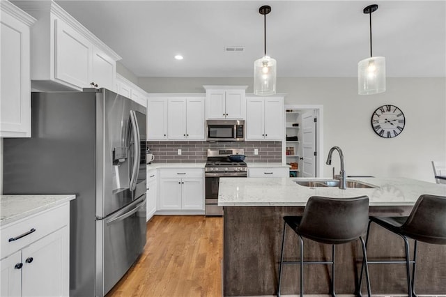 kitchen with stainless steel appliances, white cabinetry, and a sink