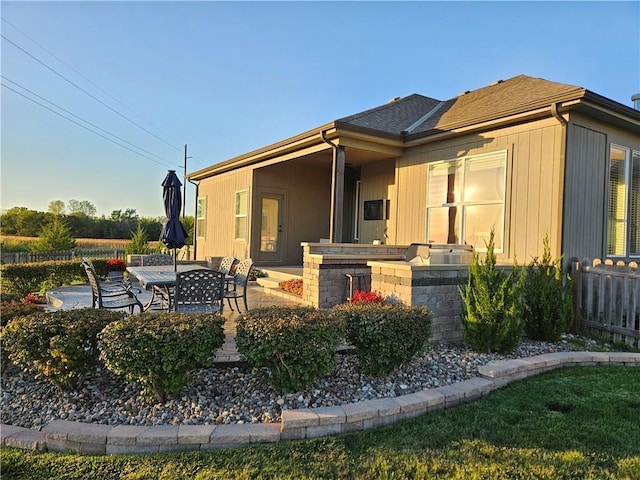 exterior space featuring a shingled roof and a patio