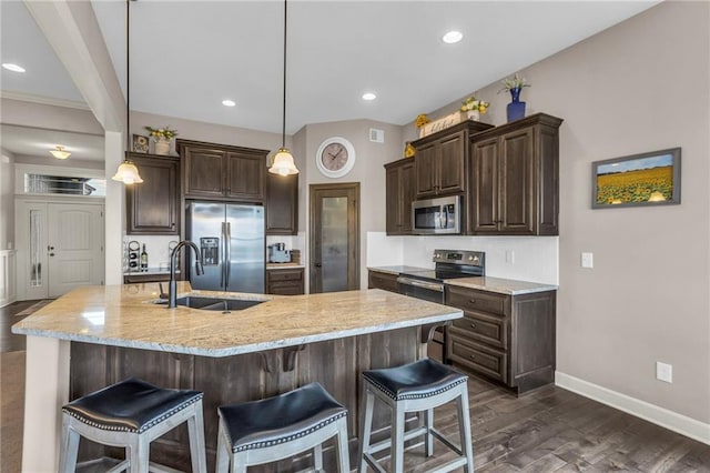 kitchen with appliances with stainless steel finishes, a breakfast bar, a sink, and dark brown cabinetry