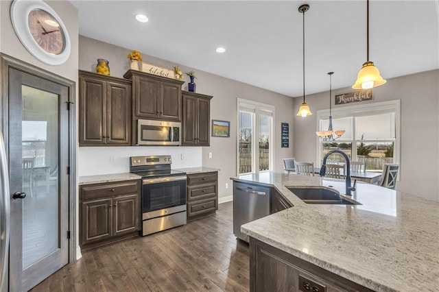 kitchen featuring stainless steel appliances, dark wood-style flooring, a sink, and dark brown cabinets