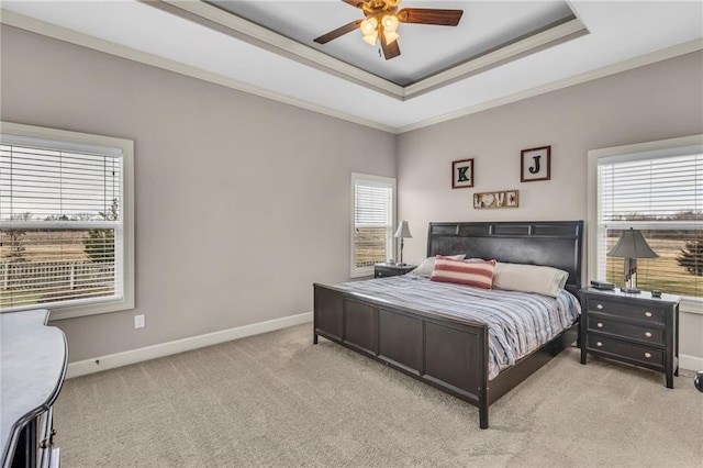 carpeted bedroom featuring a ceiling fan, baseboards, a tray ceiling, and crown molding