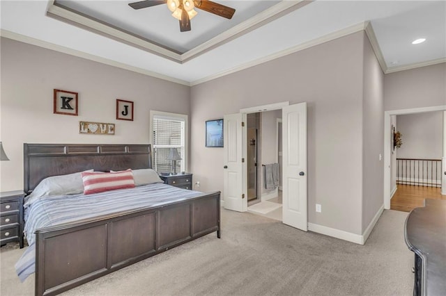 bedroom with light carpet, a tray ceiling, baseboards, and crown molding