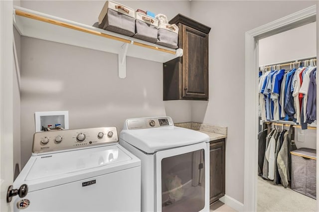 laundry area with light carpet, washing machine and dryer, cabinet space, and baseboards