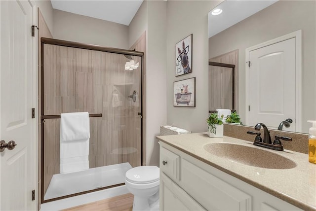 bathroom with a stall shower, vanity, and toilet