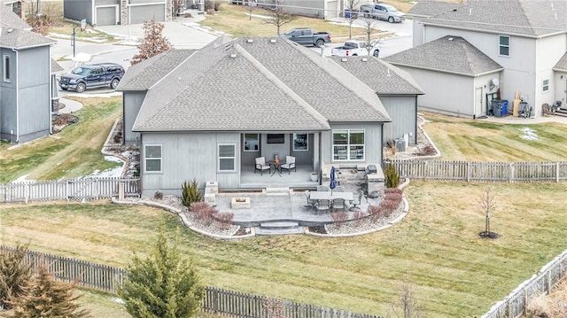 back of property with a patio, a shingled roof, a lawn, and a fenced backyard