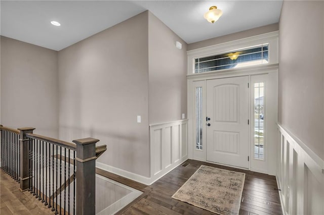 foyer entrance with a decorative wall, dark wood finished floors, and wainscoting