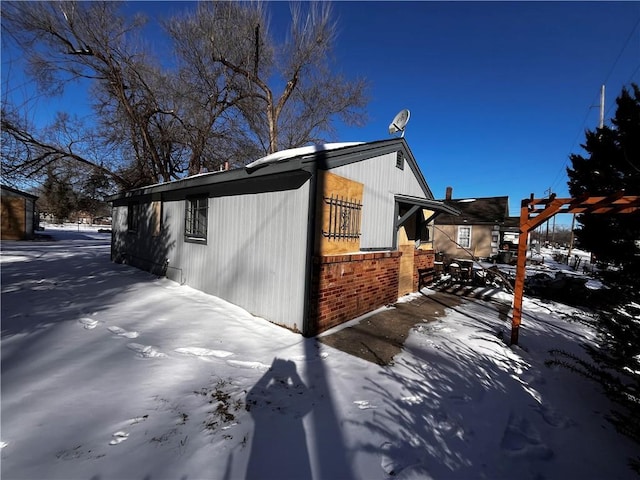 view of snow covered exterior with brick siding