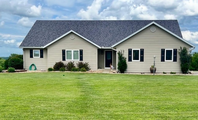 ranch-style house featuring a shingled roof and a front lawn