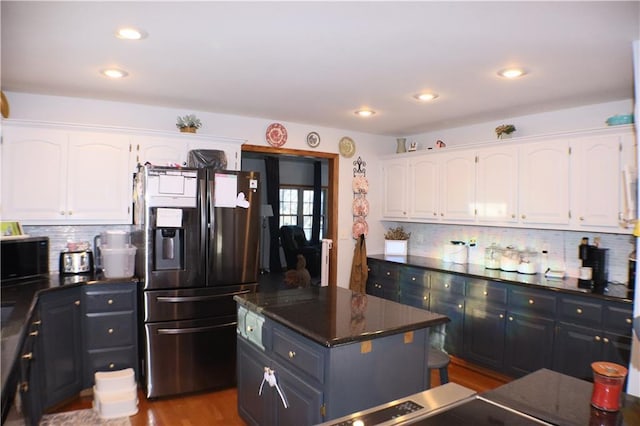 kitchen with dark countertops, white cabinetry, stainless steel refrigerator with ice dispenser, and a center island