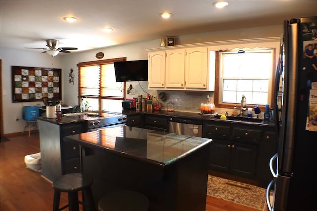 kitchen featuring a sink, a kitchen island, white cabinets, appliances with stainless steel finishes, and plenty of natural light