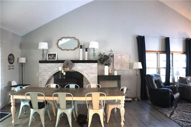 dining space featuring lofted ceiling, dark wood-type flooring, and a brick fireplace