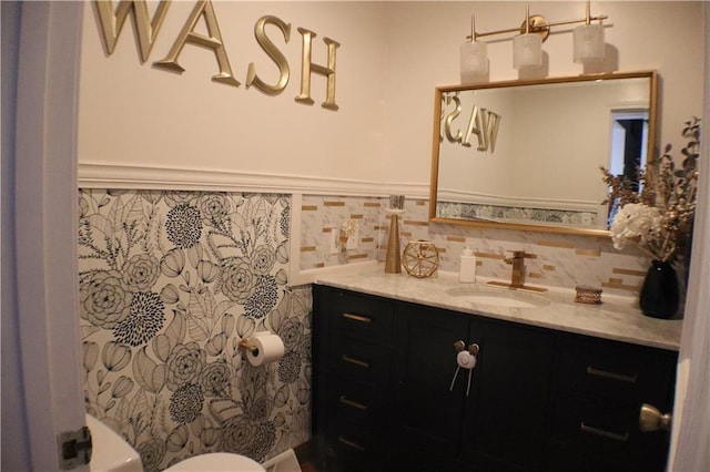 half bath featuring a wainscoted wall, toilet, vanity, and tile walls