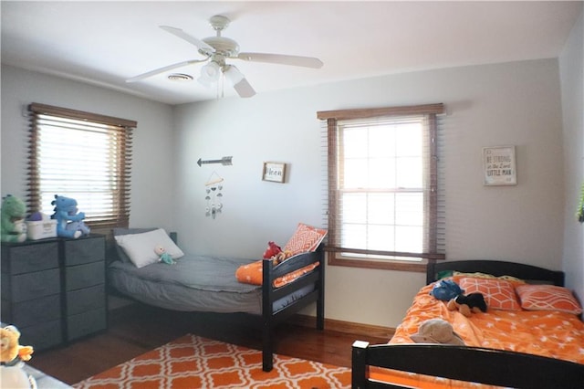 bedroom with baseboards, multiple windows, a ceiling fan, and wood finished floors