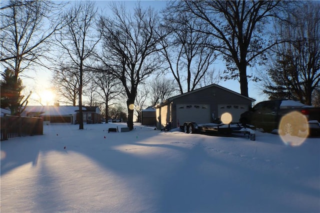 snowy yard with a garage and an outbuilding