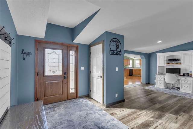 entrance foyer with vaulted ceiling, wood finished floors, and baseboards